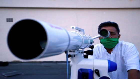 An official wearing a protective mask uses a telescope to view the moon on the roof of the Ministry of Religious Affairs building to mark the Eid al-Fitr celebrations amid the coronavirus disease (COVID-19) outbreak in Jakarta, Indonesia, May 22, 2020. REUTERS/Ajeng Dinar Ulfiana